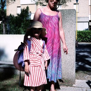 Two women outdoors, wearing retro patterned dresses and sunglasses.
