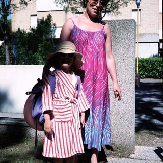 Two women outdoors, wearing retro patterned dresses and sunglasses.