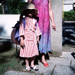 Two women outdoors, wearing retro patterned dresses and sunglasses.