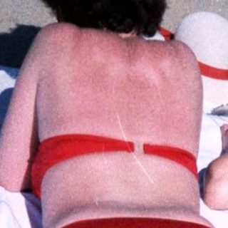 Two women mid-air on beach towels.