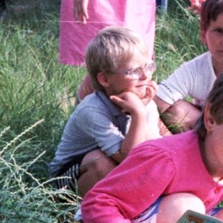 Family gardening outdoors together in a grassy area.