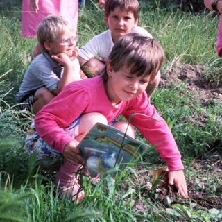 Family gardening outdoors together in a grassy area.