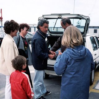 Family group near open car trunk.
