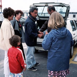 Family group near open car trunk.