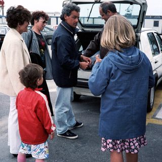 Family group near open car trunk.