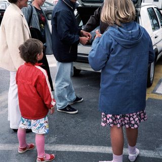 Family group near open car trunk.
