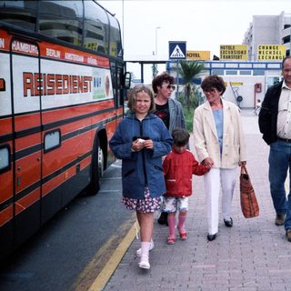 Family walking near coach with "Resident NV" label.