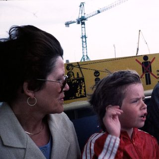 Three people observing construction site with safety sign.
