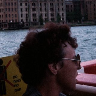 Large historic building by waterfront, viewed from boat.