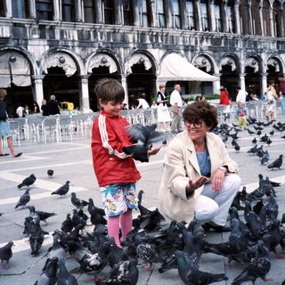 A woman and child feeding pigeons in St. Mark's Square.