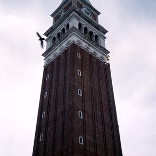 Tall brick clock tower with green roof.