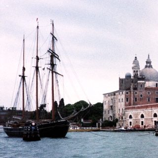 Venetian waterfront with historic basilica and sailing ship.