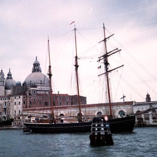 Historic ship near Venetian church and buildings.