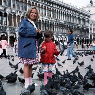 Two children feeding pigeons in St. Mark's Square.