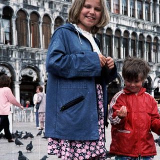 Two children feeding pigeons in St. Mark's Square.