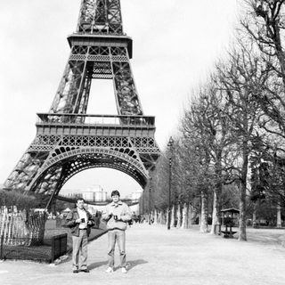 Two men posing near Eiffel Tower entrance.