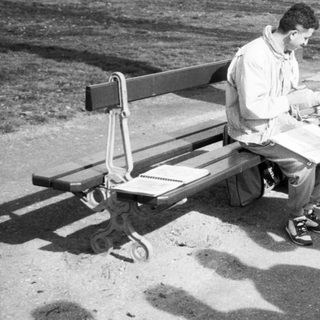 Man sitting on bench eating outdoors.