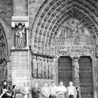 Group of men posing outside Gothic cathedral façade.