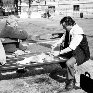 Two people sharing a meal outdoors on a bench.