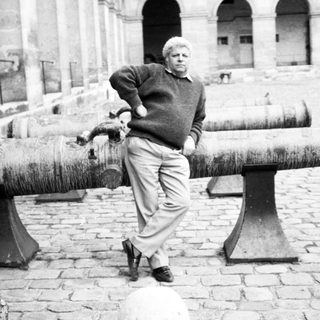 Man posing beside old cannons in courtyard.