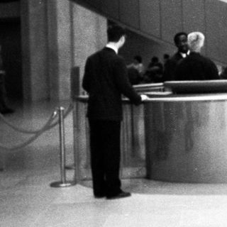 Modernist building lobby with curved staircase and reception desk.