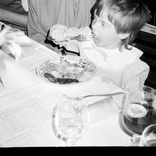 A woman and child eating together indoors.
