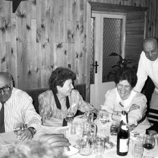 Family gathering enjoying wine and dinner together indoors.