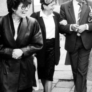 Group of people walking outdoors in 1960s-70s attire.