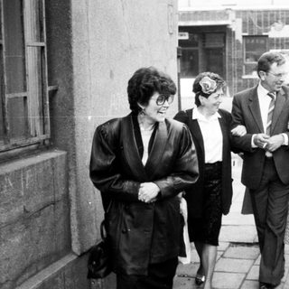Group of people walking outdoors in 1960s-70s attire.