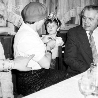 Child receiving a kiss from an older man indoors.