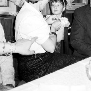 Child receiving a kiss from an older man indoors.