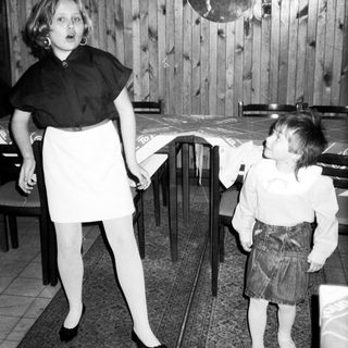 Two children playing with a balloon indoors.