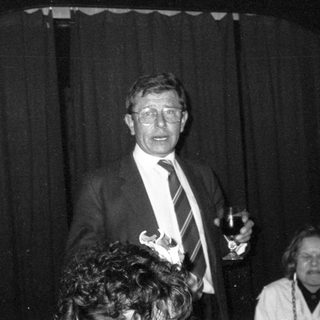 Man speaking at an indoor event with Coca-Cola branding.