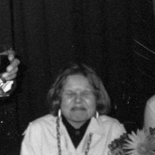 Man speaking at an indoor event with Coca-Cola branding.