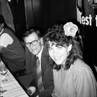 Two people smiling indoors at an event.