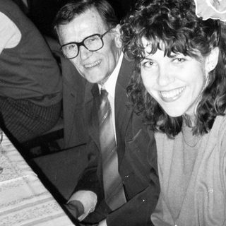 Two people smiling indoors at an event.