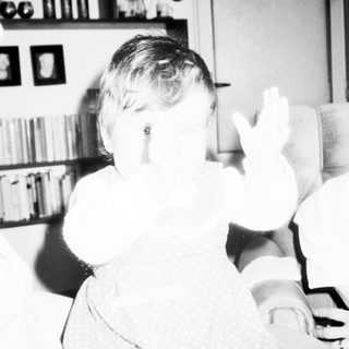 Child playing with large cardboard cutouts indoors.