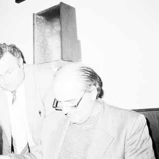 Two men examining a modern geometric sculpture indoors.