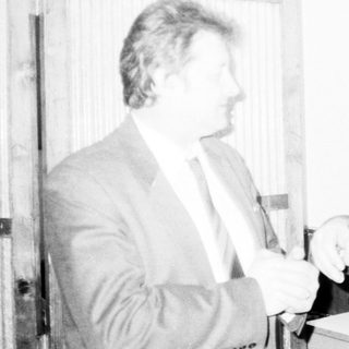 Two men exchanging a small object formally.