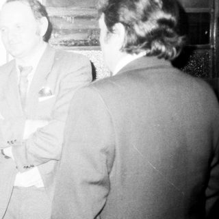 Businessmen engaged in discussion indoors.