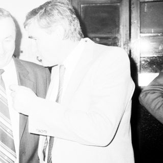 Group of men in formal attire discussing indoors.