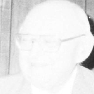 Men in formal attire at indoor meeting or event.