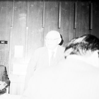 Men in formal attire at indoor meeting or event.