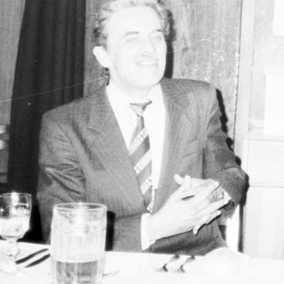 Men in formal attire at indoor meeting or event.