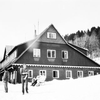 Mountain lodge with skiers in snowy landscape.