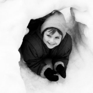 Child buried in snow, playing happily.