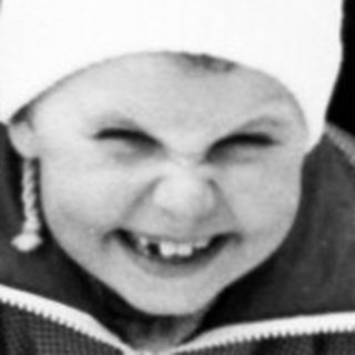 Child buried in snow, smiling happily.