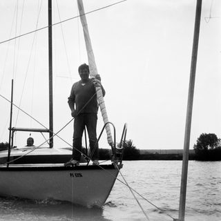 Man standing on sailboat handling ropes.