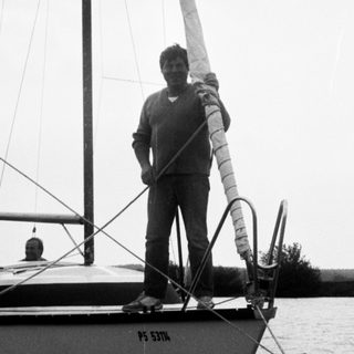 Man standing on sailboat handling ropes.