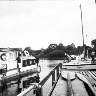 Boats docked at a marina with people.
